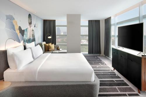 a hotel room with a large white bed and a tv at Novotel Jakarta Cikini in Jakarta
