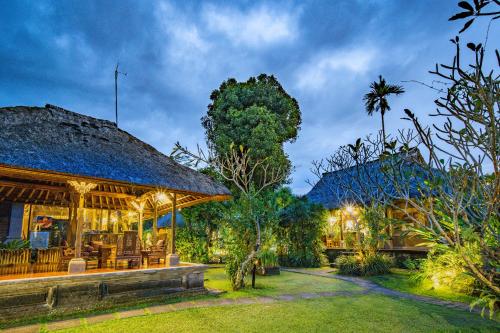 una casa con techo de paja en un jardín en Ananda Ubud Resort, en Ubud