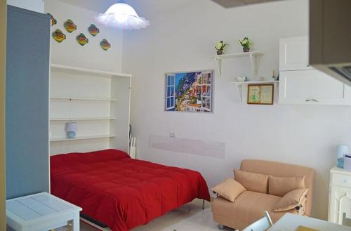 a bedroom with a red bed and a couch at LA SCALINATELLA -vista mare- in Vietri sul Mare