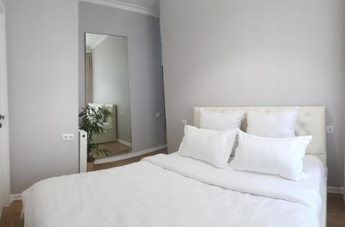 una cama blanca con almohadas blancas y un espejo en Mtatsminda, en Tiflis