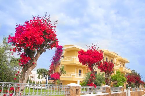 a yellow house with red flowers in front of it at Parthenis Hotel & Suites in Malia