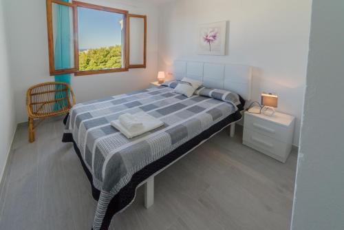 1 dormitorio con 1 cama grande y ventana en Vistas al mar y la piscina en Arenal d'en Castell