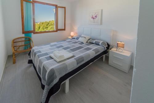 Un dormitorio con una cama grande con ventana. en Vistas al mar y la piscina, en Arenal d'en Castell