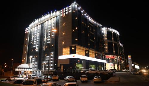 a large building with cars parked in a parking lot at Borj Al Thahabiah ApartHotel in Taif