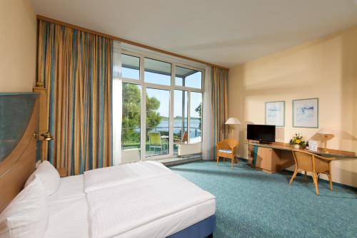 a hotel room with a bed and a desk at Hotel Bollmannsruh am Beetzsee in Päwesin