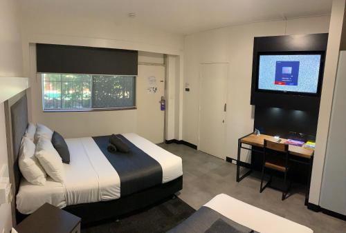 Habitación de hotel con cama, escritorio y TV. en The Stuart Hotel-Motel, en Katherine