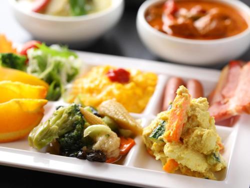 a white plate of food with broccoli and other foods at APA Hotel Shinjuku Kabukicho Chuo in Tokyo