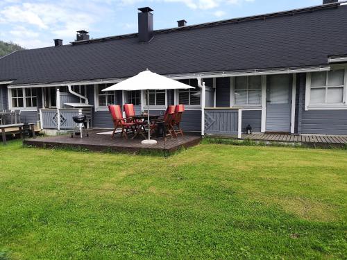 a house with a patio with chairs and an umbrella at Aaria Apartment in Tahkovuori