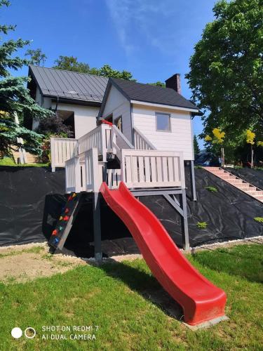 a playground with a slide in front of a house at Domek w dolinie in Berest