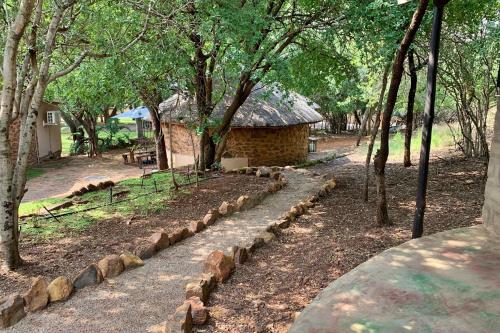 a stone building with a thatched roof in a forest at Shala Mushe Tented Camp & Camp in Bela-Bela