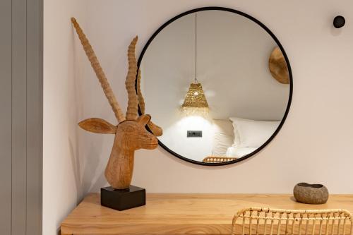 a room with a mirror and a wooden deer head on a table at Lemon Suites Santorini in Fira