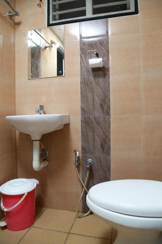 a bathroom with a sink and a toilet and a mirror at El Casa Homestay in Cochin