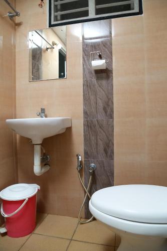 uma casa de banho com um lavatório, um WC e um espelho. em El Casa Homestay em Cochin
