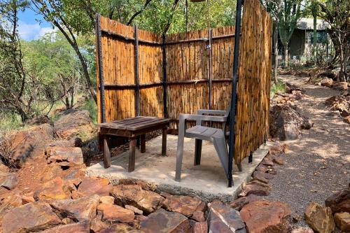 a bench next to a wooden fence and a wooden table at Shala Mushe Tented Camp & Camp in Bela-Bela