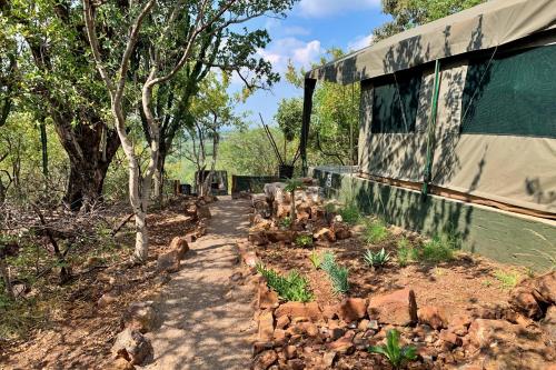 a dirt path next to a building with trees at Shala Mushe Tented Camp & Camp in Bela-Bela