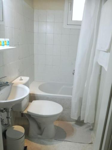 a white bathroom with a toilet and a sink at Sweet Home (50m from center Lithostroto) in Argostoli