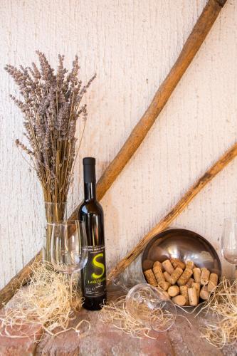 a bottle of wine next to a vase and a bowl of peanuts at Vinska klet Smej in Lendava
