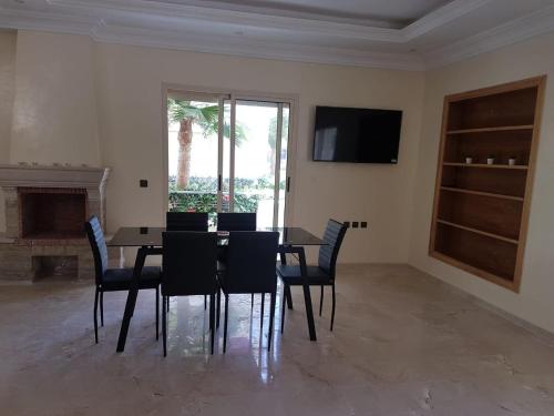 a dining room with a table and chairs and a television at Magnifique Villa a Savannah Beach in Sidi Rahal