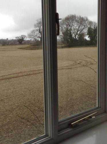 a view of a field through a window at The Garden Loft in Freethorpe