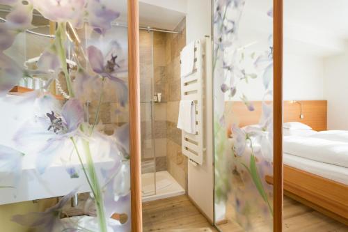 a room with a shower with purple flowers on the wall at Hotel Heubad in Fiè