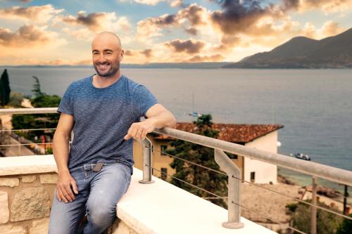 a man sitting on a ledge next to the water at Sunset Residence in Brenzone sul Garda