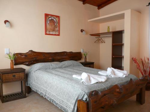 a bedroom with a large wooden bed with towels on it at Cabañas Señales in San Marcos Sierras