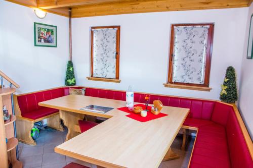 uma cabina vermelha com uma mesa de madeira e cadeiras vermelhas em Brunarica Čontoš em Lendava