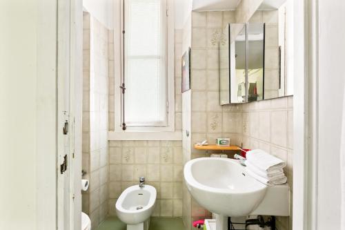 biała łazienka z umywalką i toaletą w obiekcie Cenisio & Sempione Cosy Flat w Mediolanie