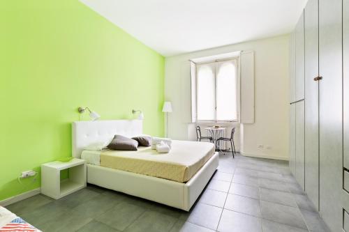 zieloną sypialnię z łóżkiem i stołem w obiekcie Cenisio & Sempione Cosy Flat w Mediolanie