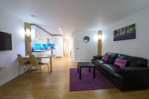 a living room with a black leather couch and a table at Zinn Apartments - City Centre in Aberdeen