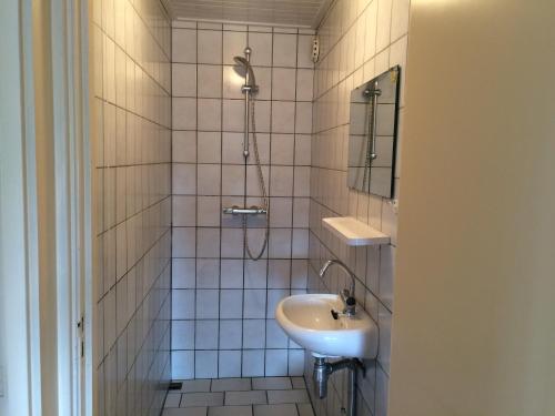 a white tiled bathroom with a sink and a shower at B&B Nobel in Buren