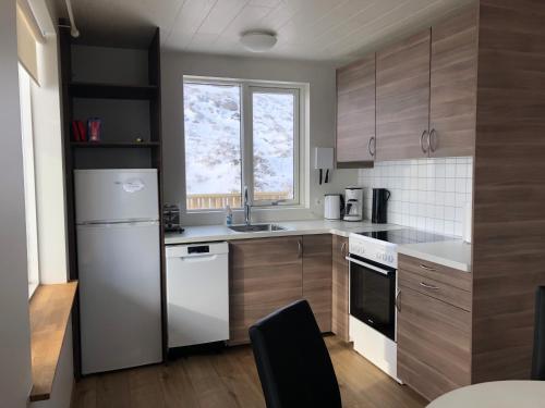 a kitchen with a white refrigerator and wooden cabinets at Mosas cottages in Fludir