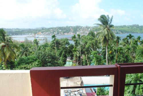 a balcony with a view of the water and palm trees at Roxel Inn in Port Blair