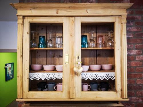 a wooden cabinet with cups and dishes in it at Millenium Inn Ferienwohnung Top 2 in Mürzzuschlag