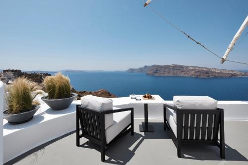 a table and chairs on a balcony with a view of the ocean at Charisma Suites in Oia
