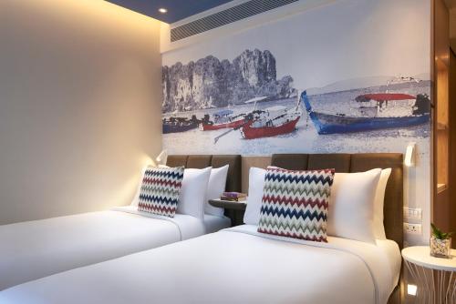 two beds in a hotel room with a painting on the wall at OZO Phuket in Kata Beach