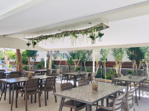 un restaurante con mesas, sillas y plantas en Tasiana Star Complex, en Limassol