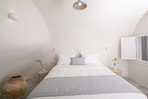 a white bedroom with a large bed with white walls at Aloia Villas in Oia