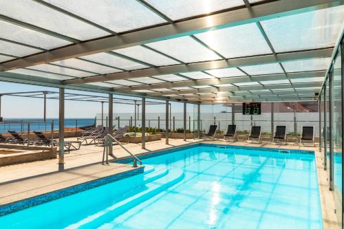 an indoor swimming pool with a large glass ceiling at Hotel Boa - Vista in Porto