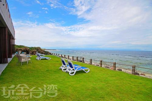 two chairs sitting on the grass near the ocean at Mediterranean B&B in Green Island