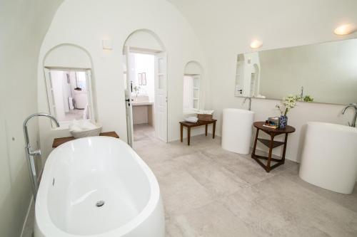 a bathroom with a white tub and two sinks at Aloia Villas in Oia