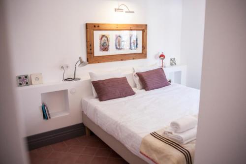 1 dormitorio con 1 cama con sábanas blancas y almohadas marrones en Casa do Lado, en Vila Nova de Milfontes