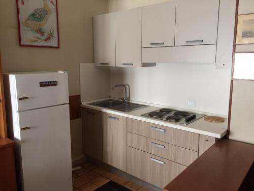 una cucina con armadi bianchi, lavandino e frigorifero di Relax e confort nella Perla dello Ionio a Soverato Marina