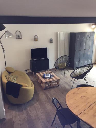 uma sala de estar com um sofá, uma mesa e cadeiras em le gite de Jules em Azay-le-Rideau