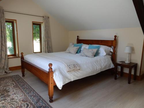 a bedroom with a large wooden bed with blue pillows at Marion's Cottage in Le Mesnil-Villeman