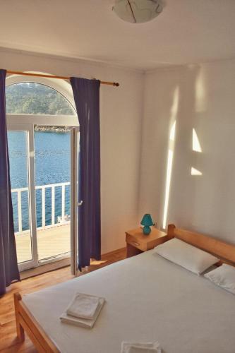 a bedroom with a bed and a large window at Mljet Sunset Apartments in Pomena