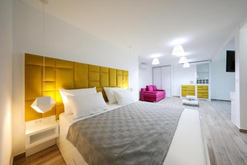 sypialnia z dużym łóżkiem i różowym krzesłem w obiekcie Boutique Residence Cosmopolis 1 w Bibinje
