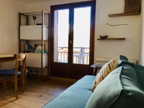 a living room with a couch and a window at Appartement cosy et chaleureux à Megève avec vue sur le Mont Blanc in Demi-Quartier