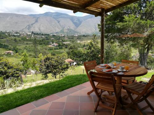 una mesa y sillas en un patio con montañas al fondo en Casa del Sol, en Villa de Leyva