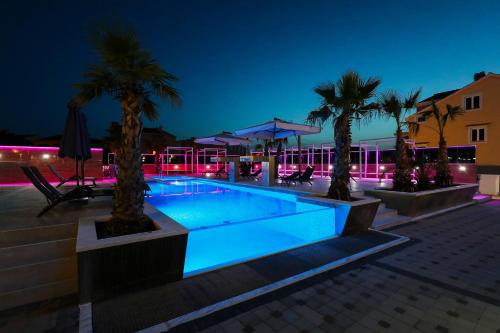 a swimming pool with palm trees in front of a building at Boutique Apartments Ad Astra in Bibinje